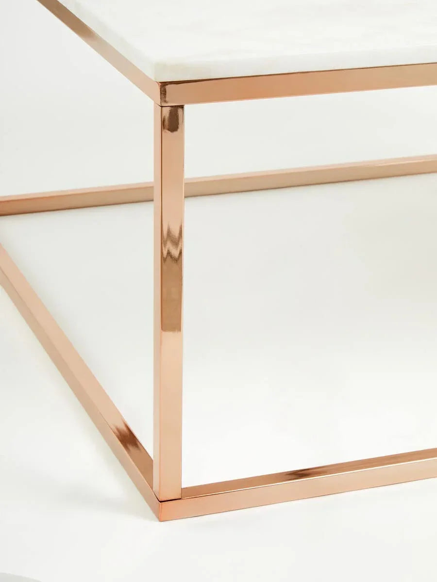 Modern coffee table with white marble top and rose gold metal frame, corner detail view