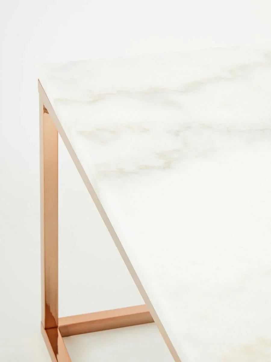 White marble table with rose gold metal frame, close-up corner view