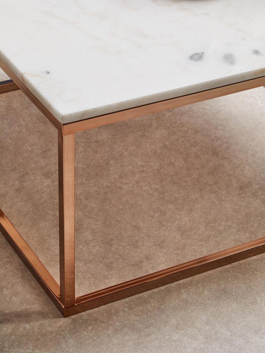 White marble coffee table with copper metal frame on neutral carpet