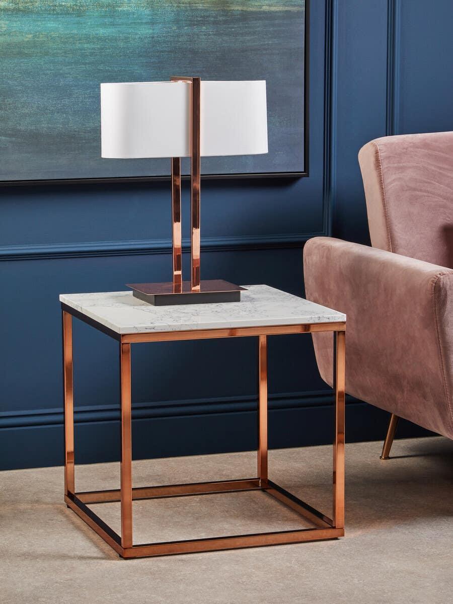 Marble top side table with copper metal frame beside blush velvet armchair
