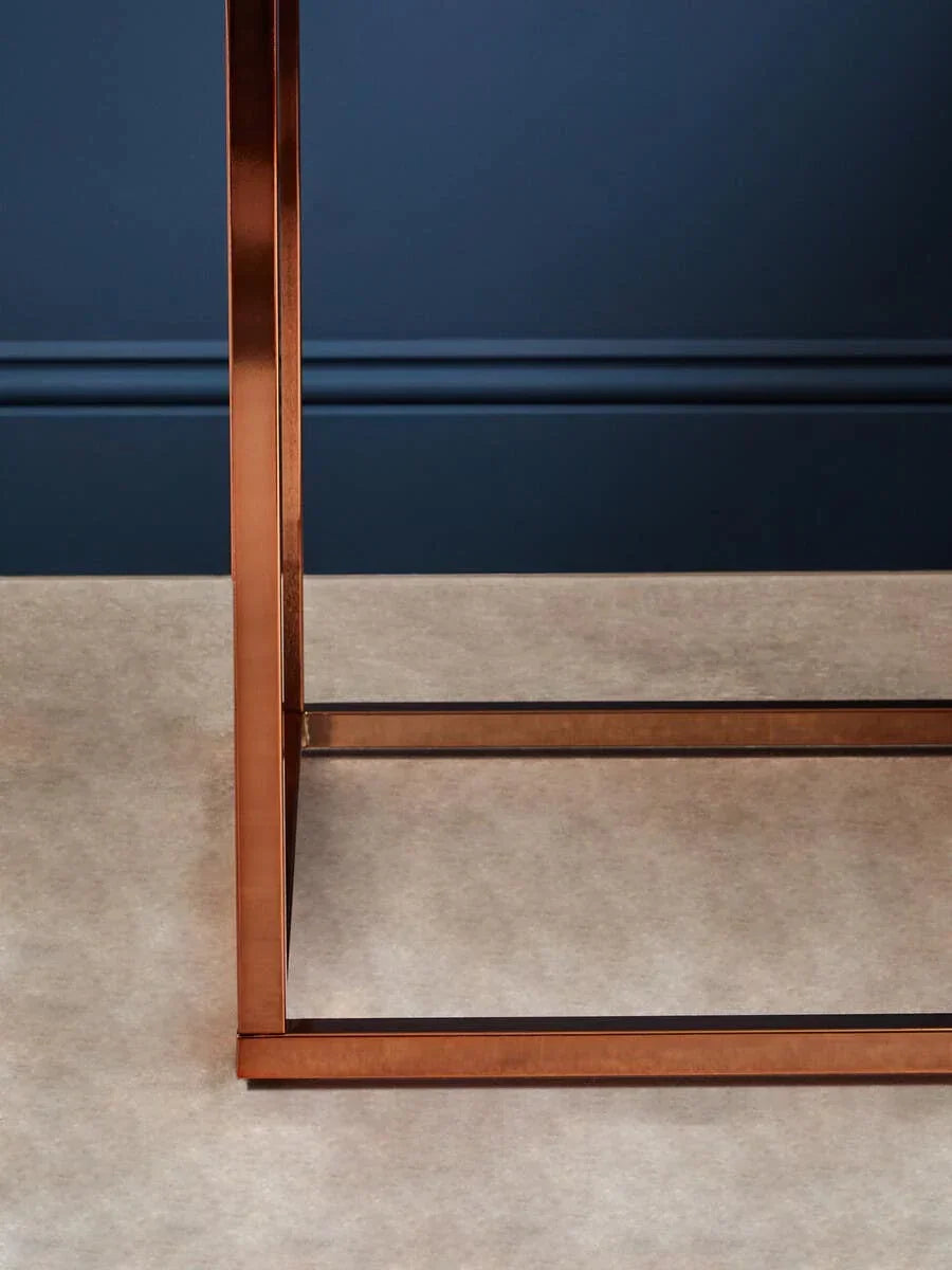Copper metal table leg frame with clean lines on neutral carpet and blue wall background