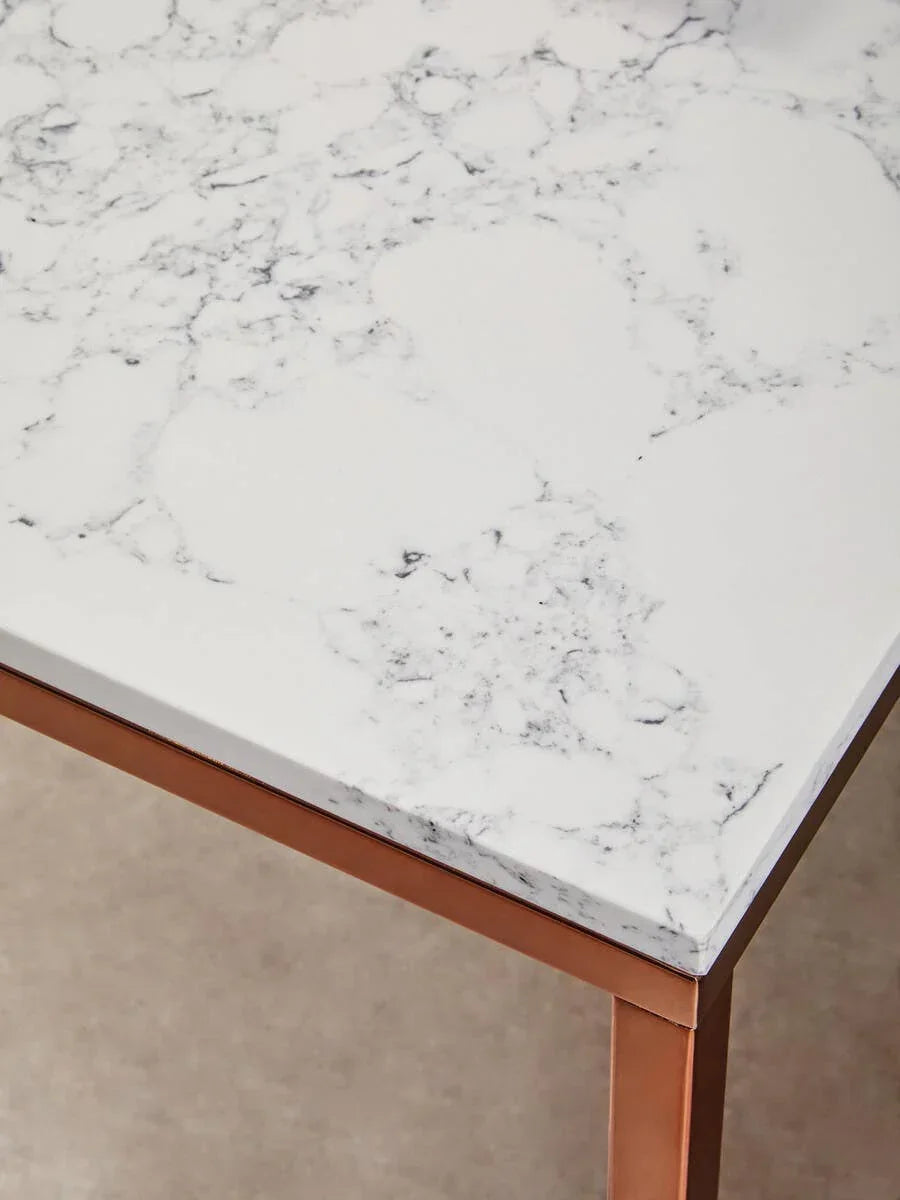 White marble dining table with copper metal legs, close-up of corner detail