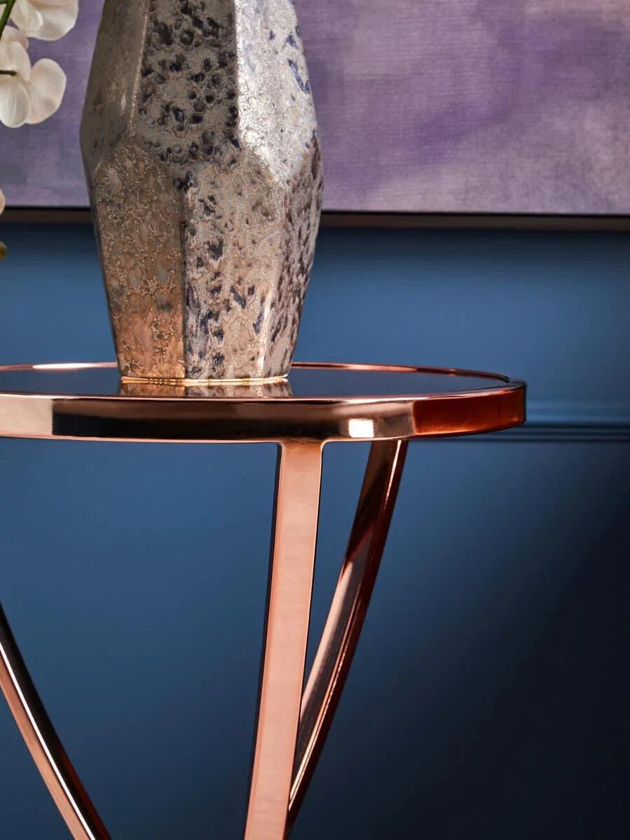 Rose gold metal side table with vase against blue wall and abstract art