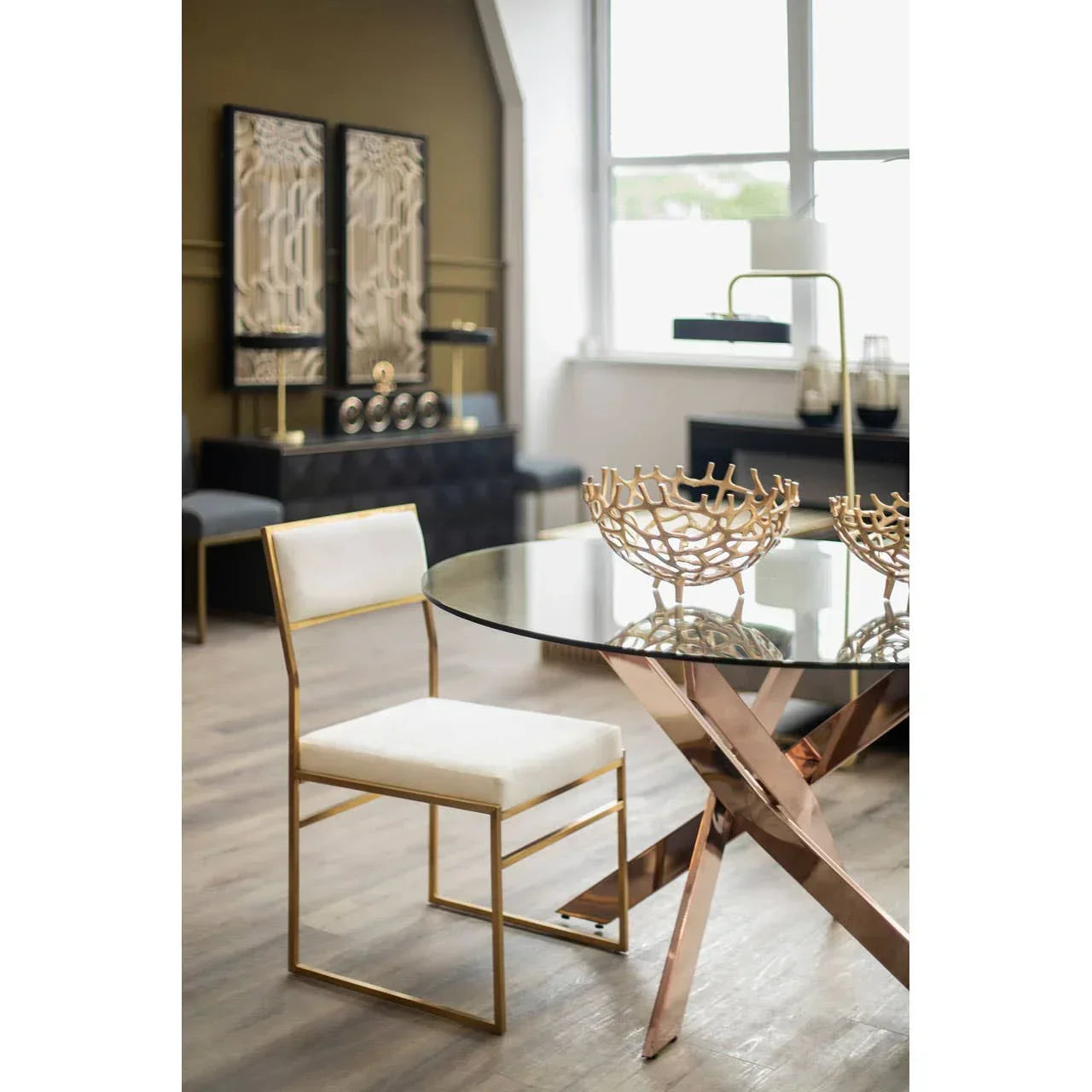 Glass dining table with gold metal legs and white chair in modern dining room