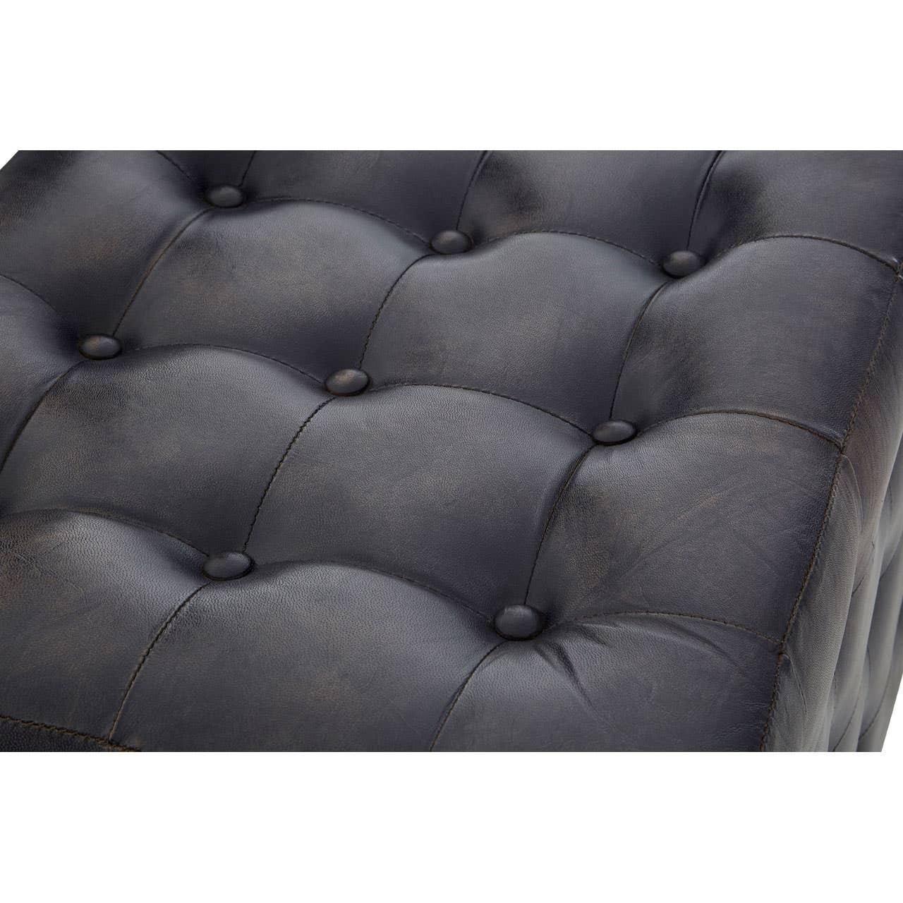 Close view of black leather ottoman with deep button tufting and stitched detail