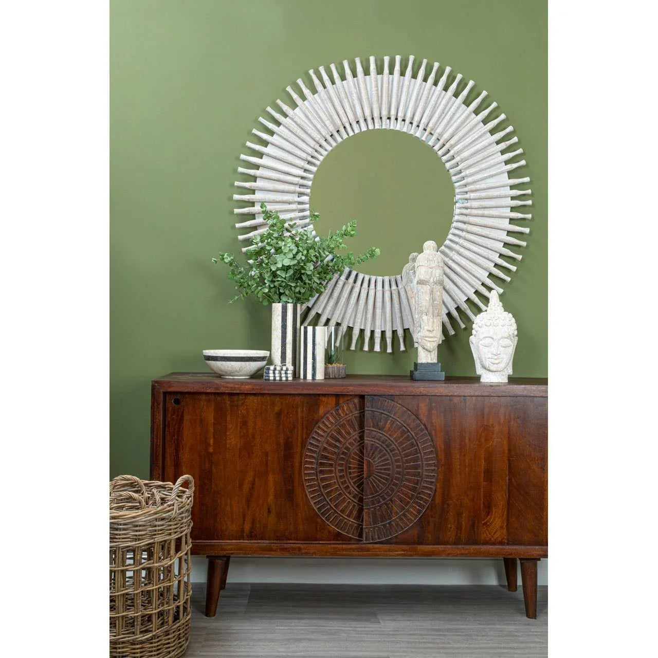 Mid-century wooden sideboard with carved doors, round mirror and home decor accents