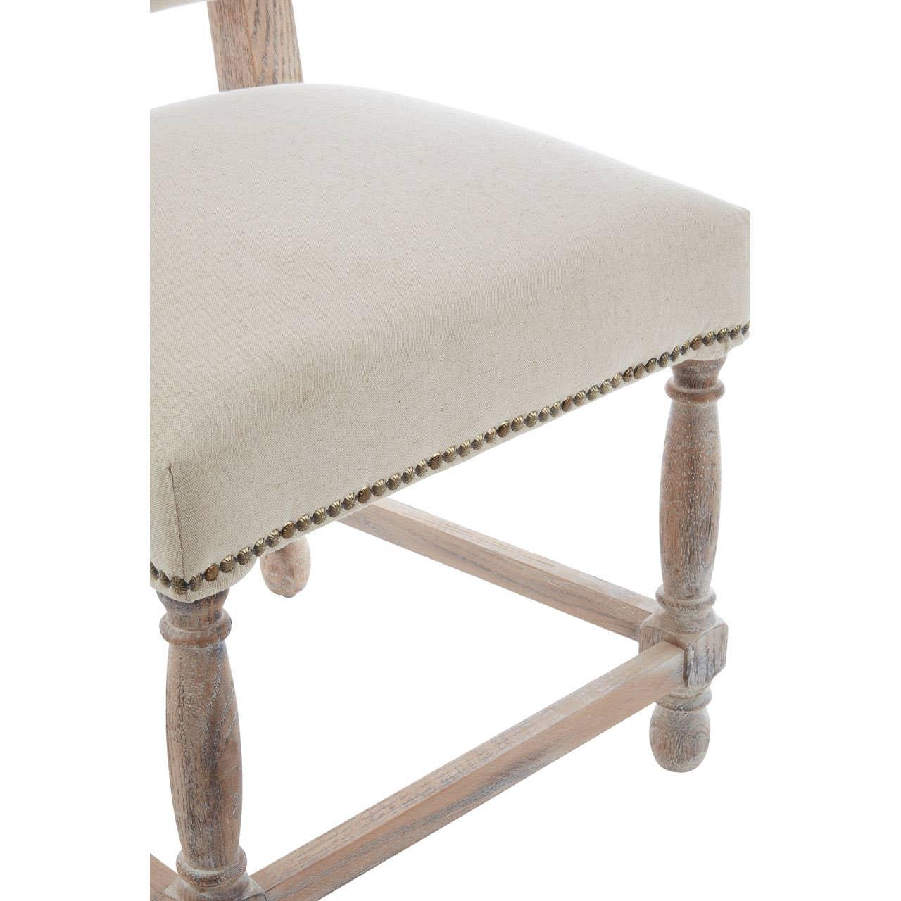 Beige upholstered dining chair seat with wooden legs and brass stud trim