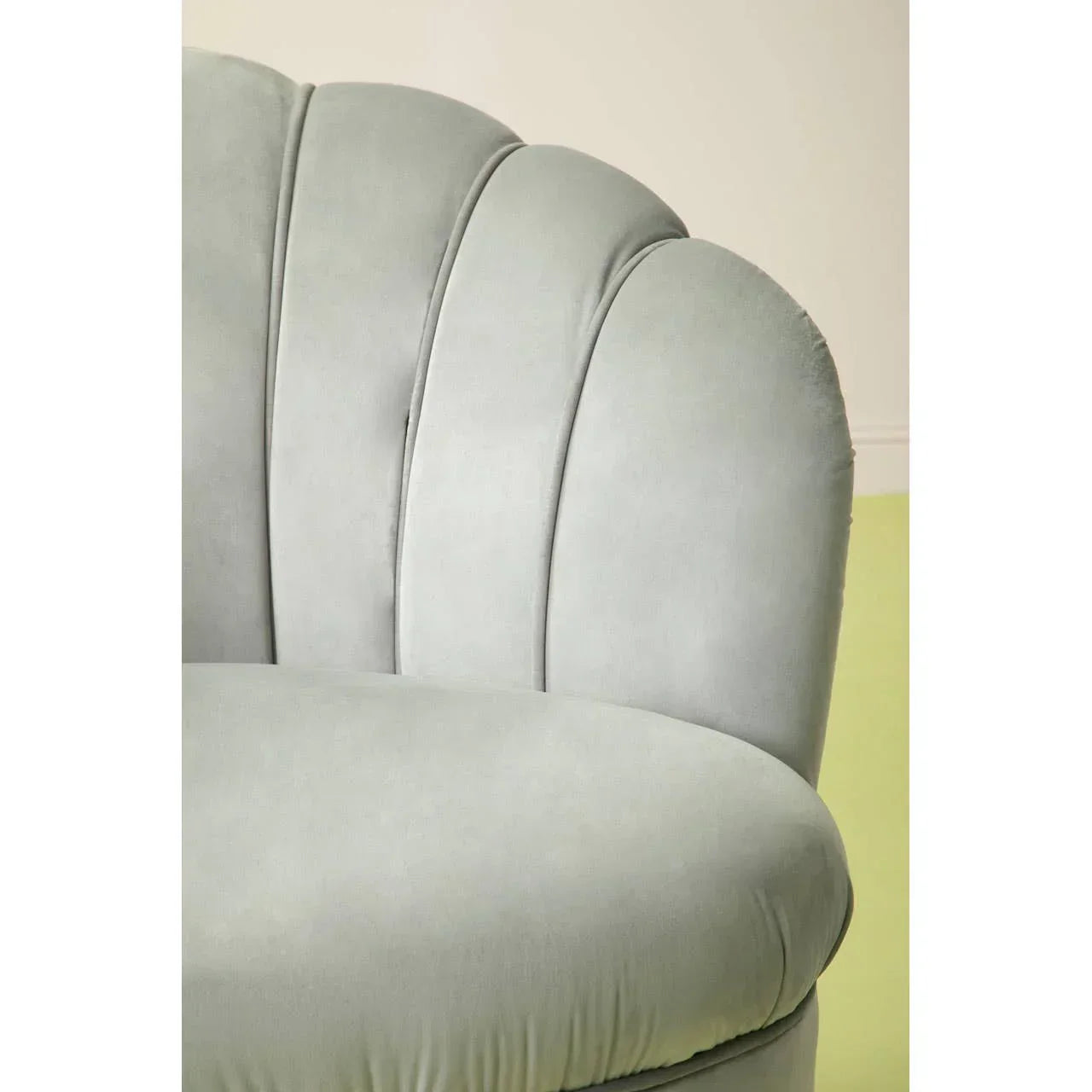 Light grey velvet sofa with scalloped backrest and rounded cushion close-up