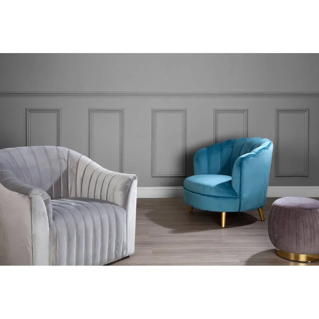 Grey velvet accent chair, blue armchair, and round pouffe with gold base on wood floor