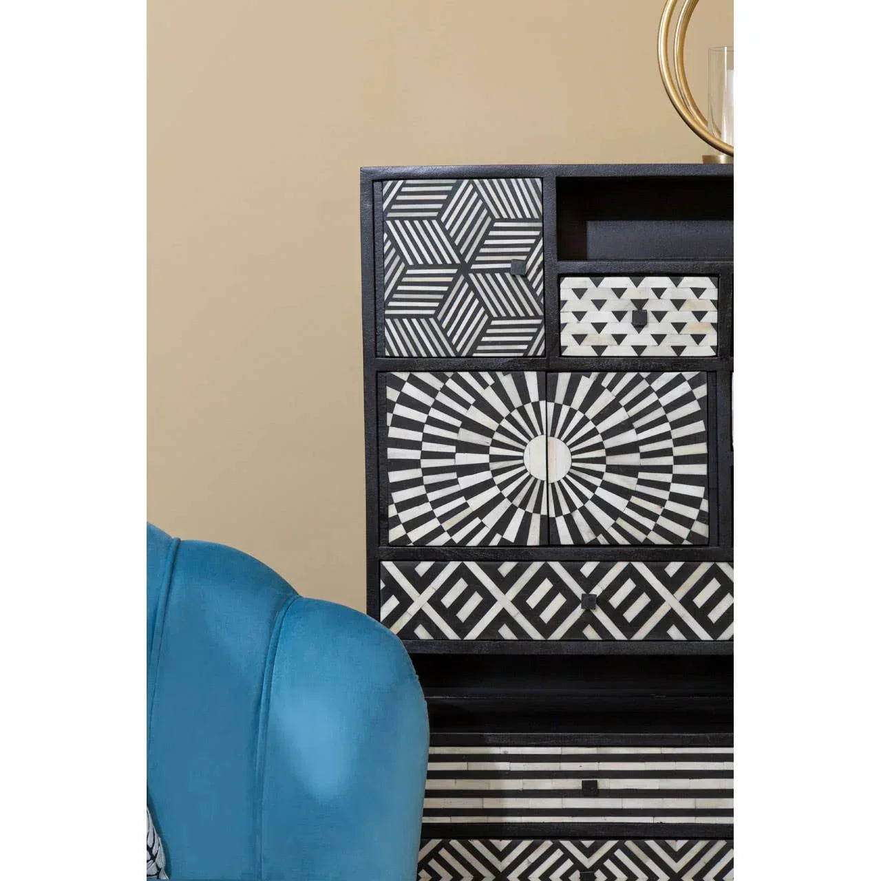 Black and white geometric chest of drawers with blue armchair and gold decorative accent