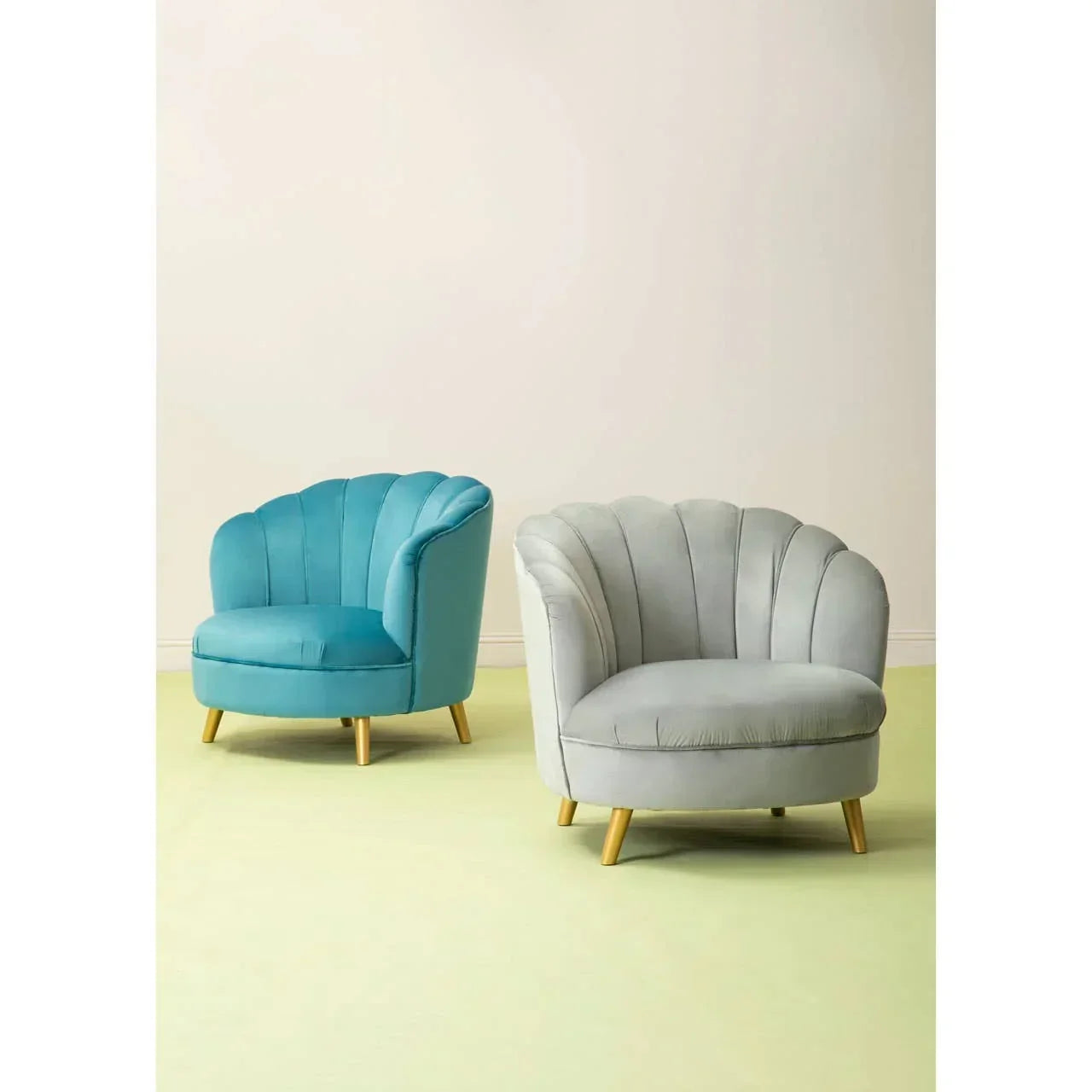 Blue and grey velvet accent chairs with scalloped backs and wooden legs on pastel floor