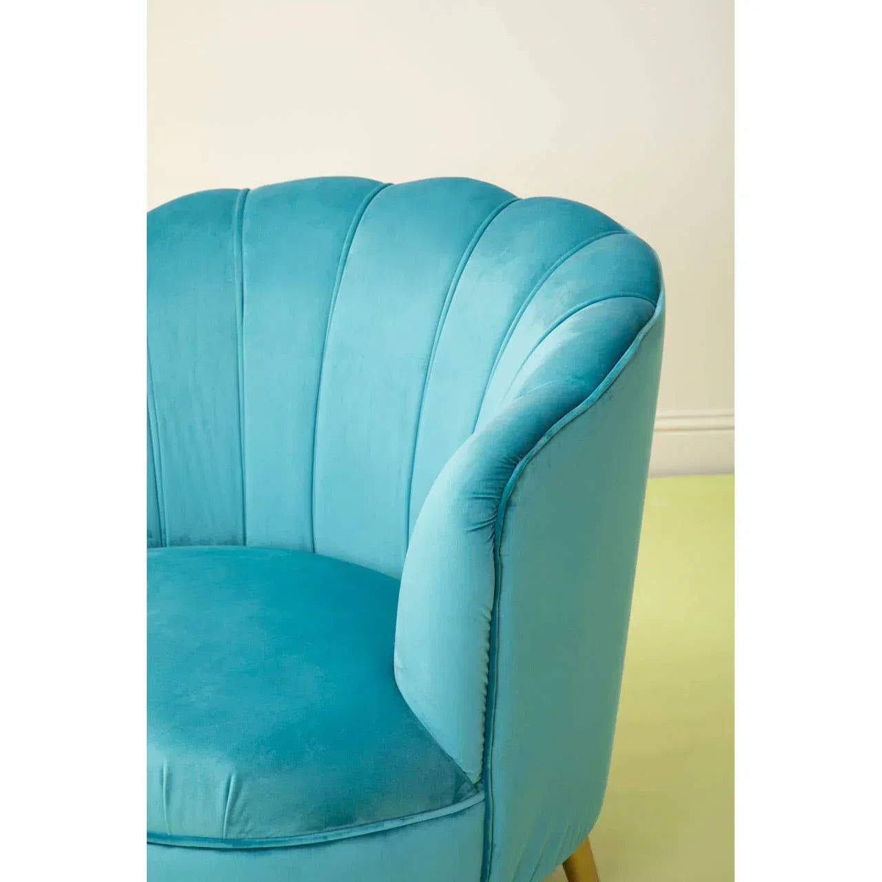 Blue velvet armchair with scalloped backrest and curved arm, close up view