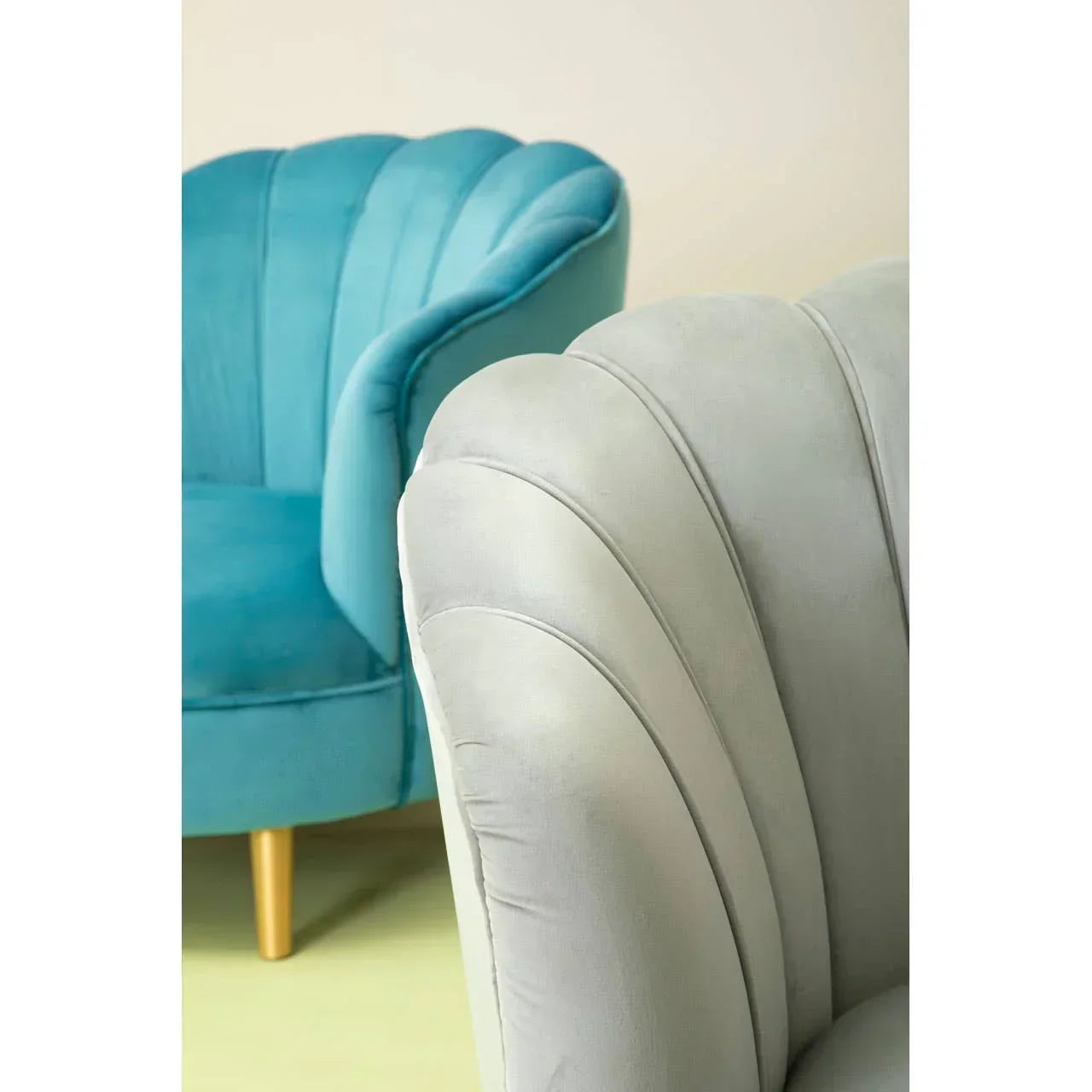 Close up of grey and teal velvet accent chairs with scalloped backrest detailing