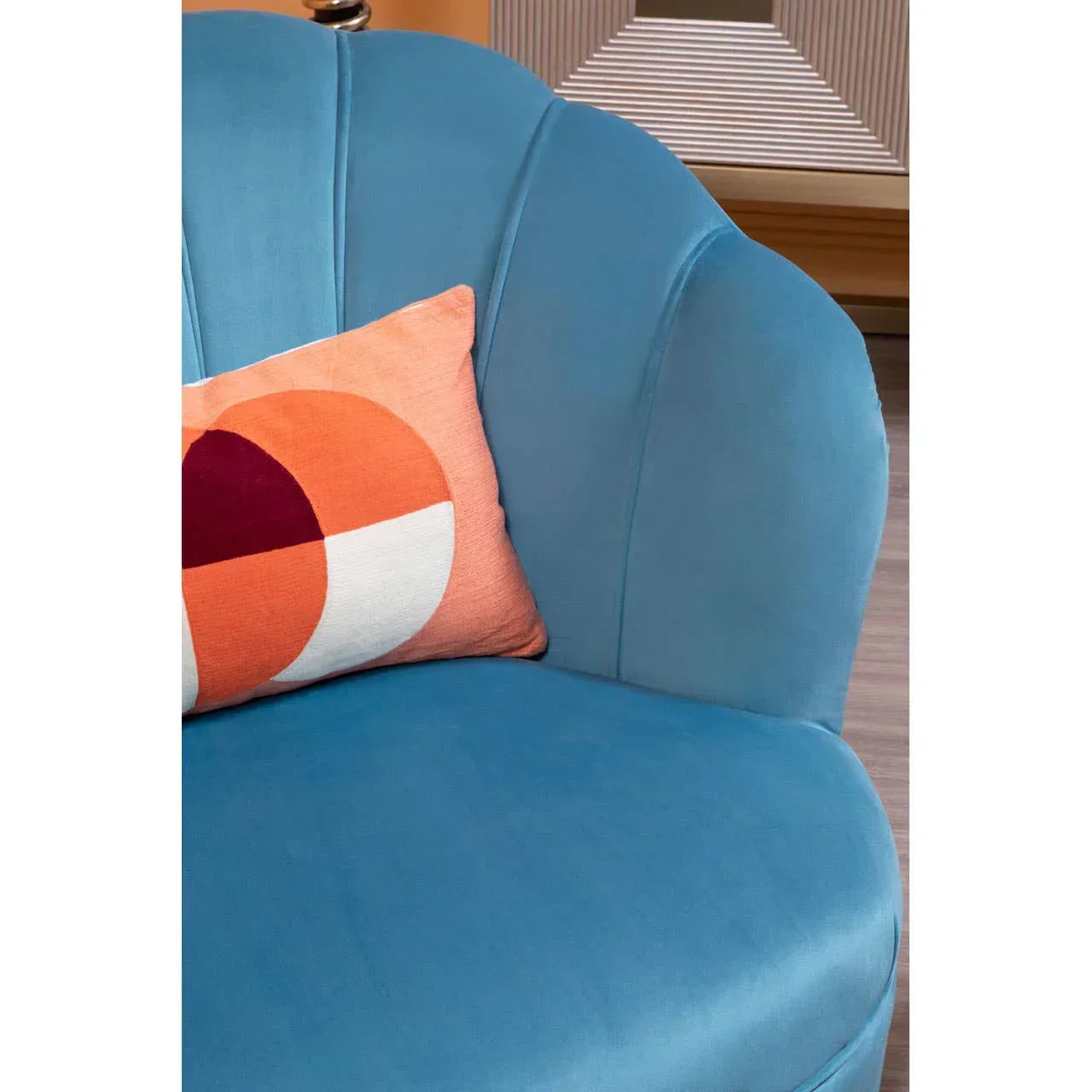 Blue velvet accent chair with scalloped backrest and orange geometric cushion