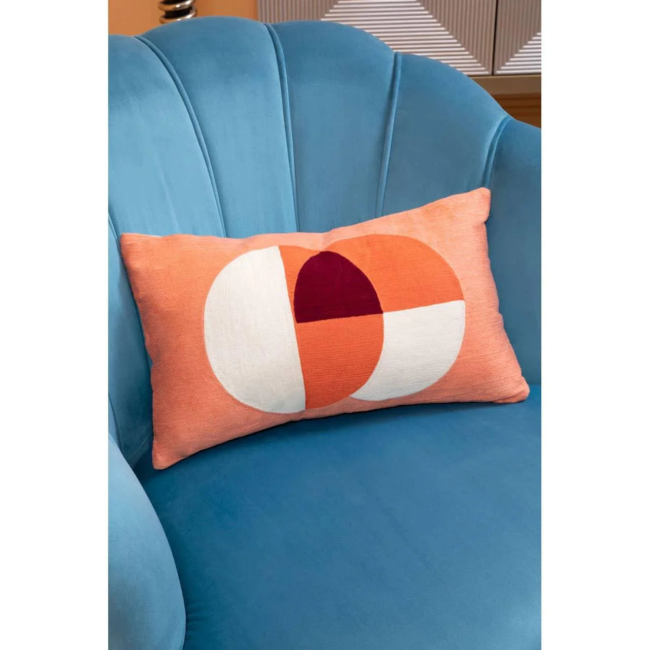Geometric orange and white cushion on blue velvet sofa