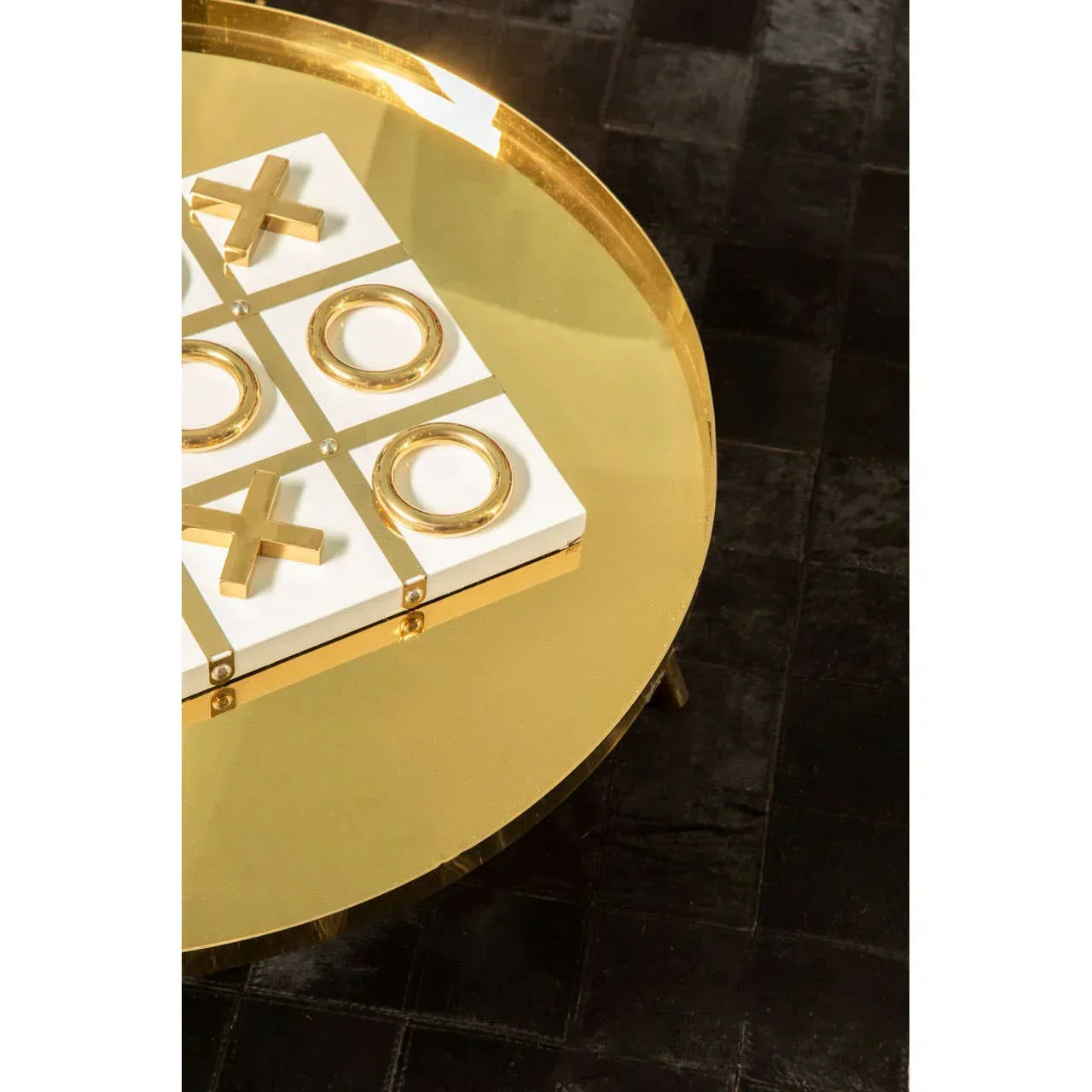 Gold round coffee table with metallic tic-tac-toe game on black textured rug