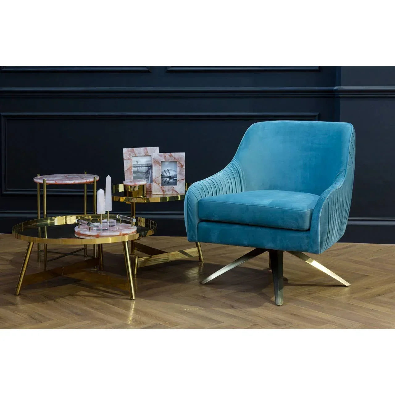 Blue velvet accent chair with gold swivel base next to marble and gold coffee table set