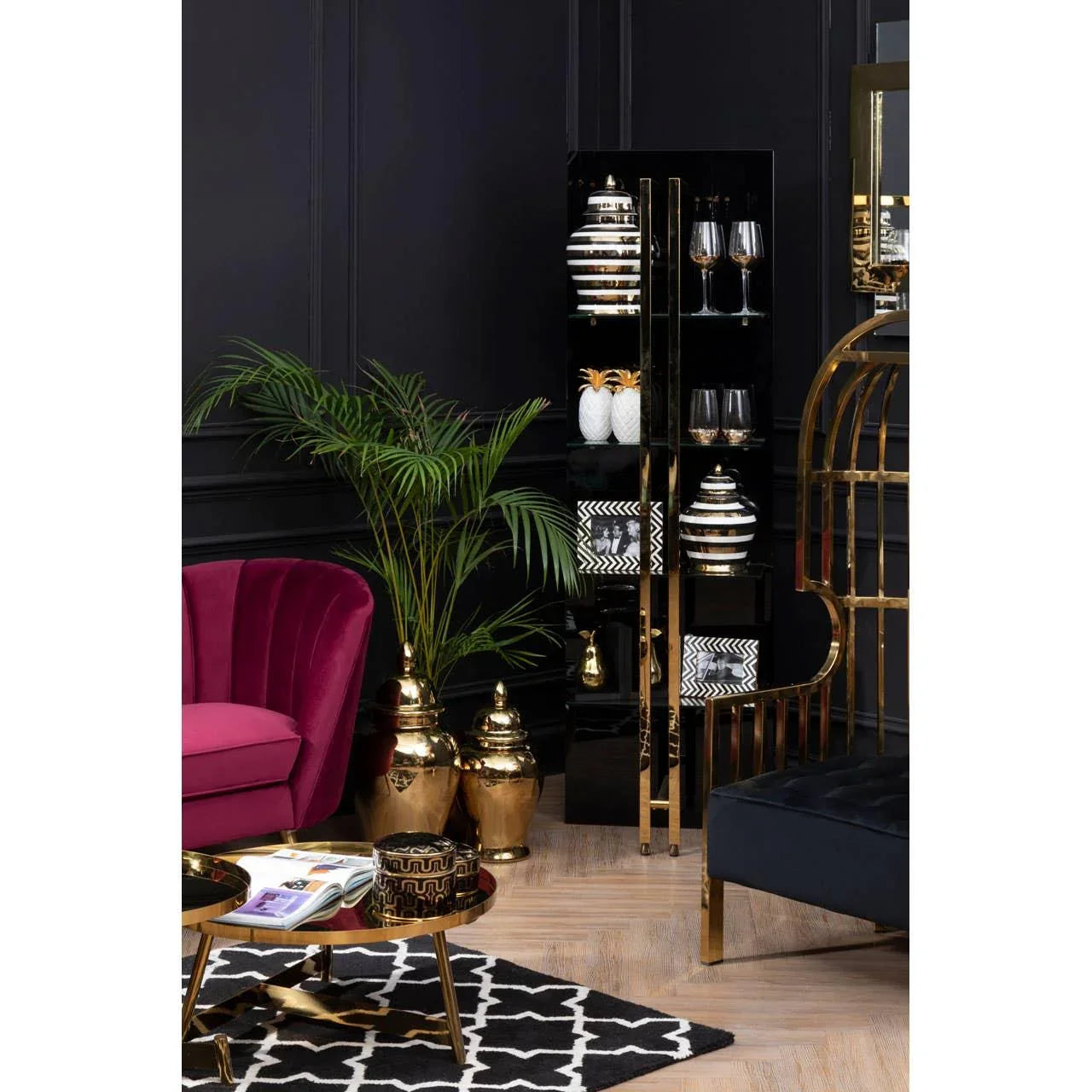 Modern black and gold living room with velvet sofa, display cabinet, palm, and coffee table