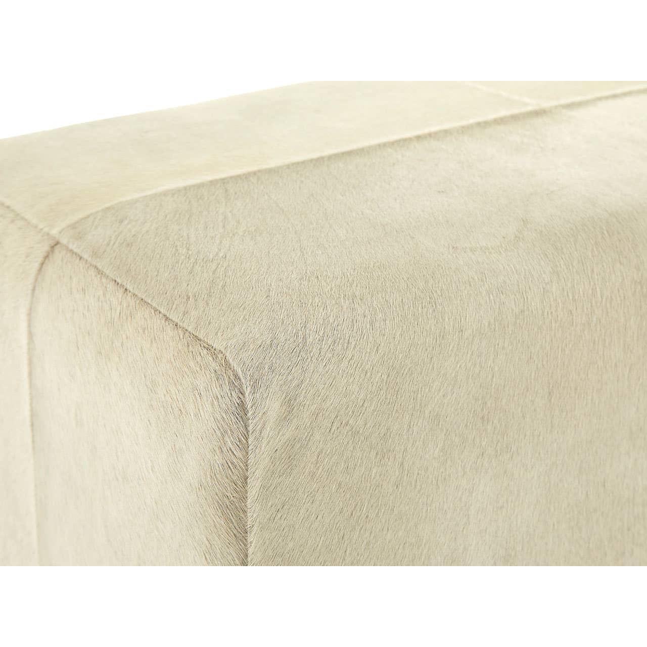 Beige cowhide leather ottoman corner with visible stitched seam and soft texture