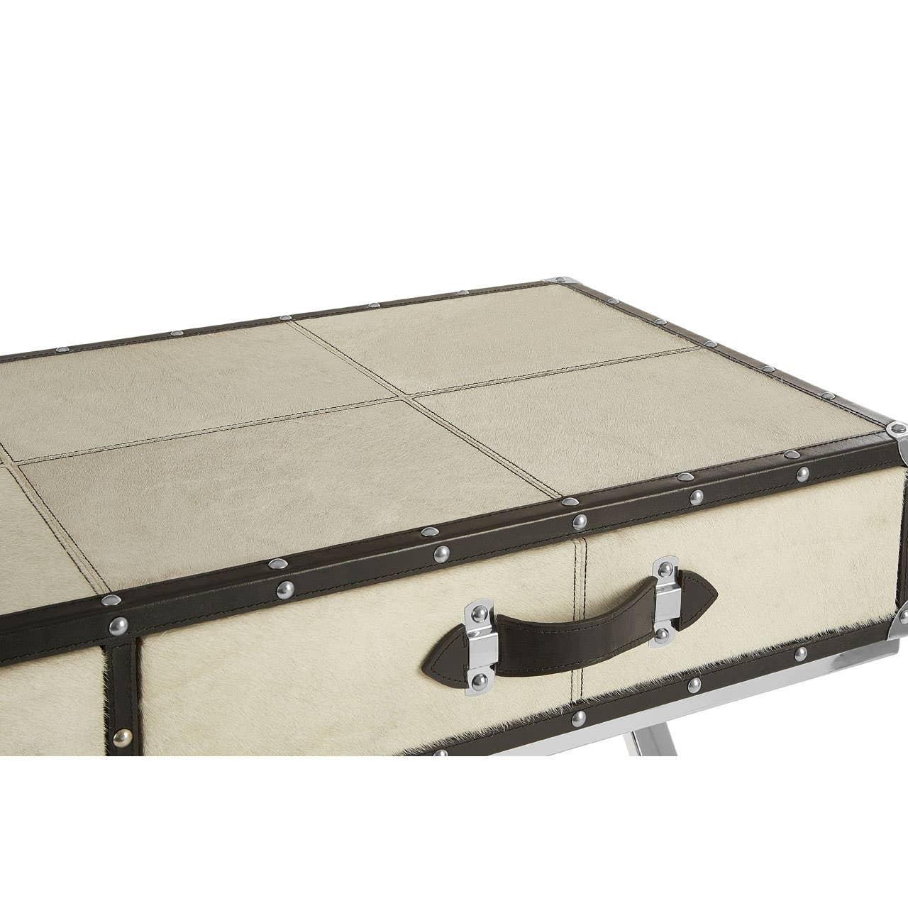 Close-up of cream leather trunk coffee table with dark trim and metal handle detail