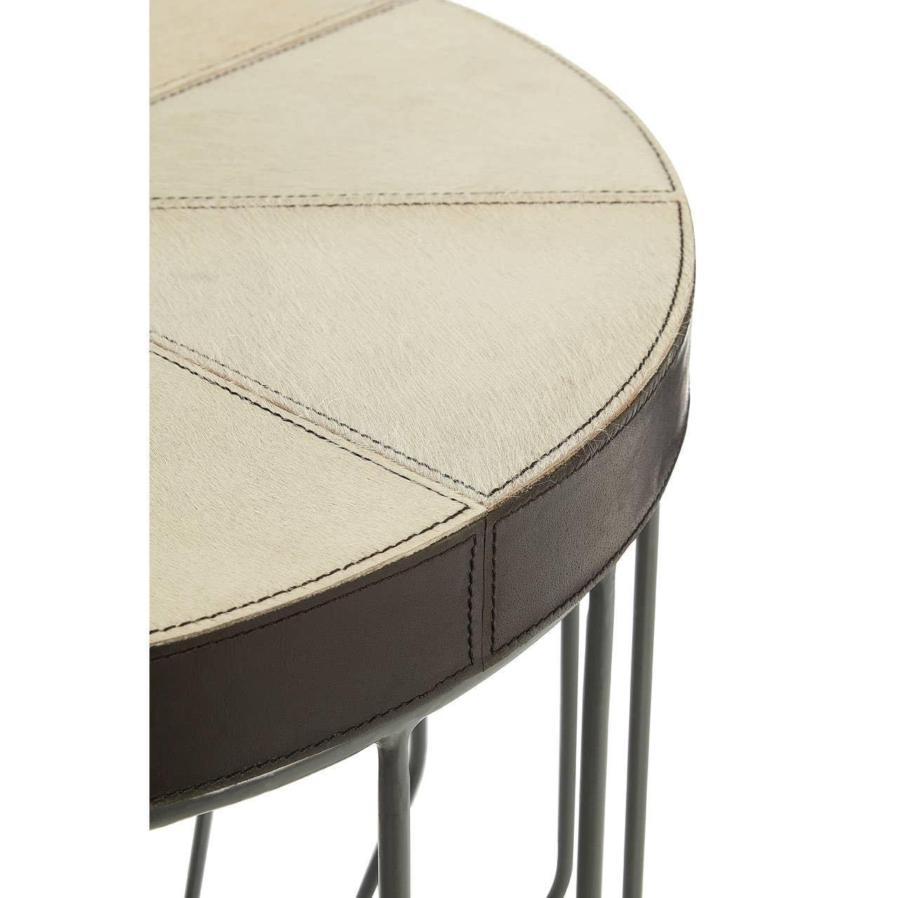 Round side table with cream patchwork top, brown trim, and metal legs, closeup view