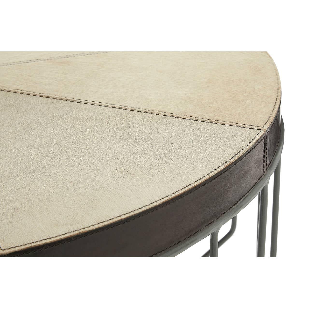 Round coffee table with stitched cream leather top and black metal frame, close-up angle