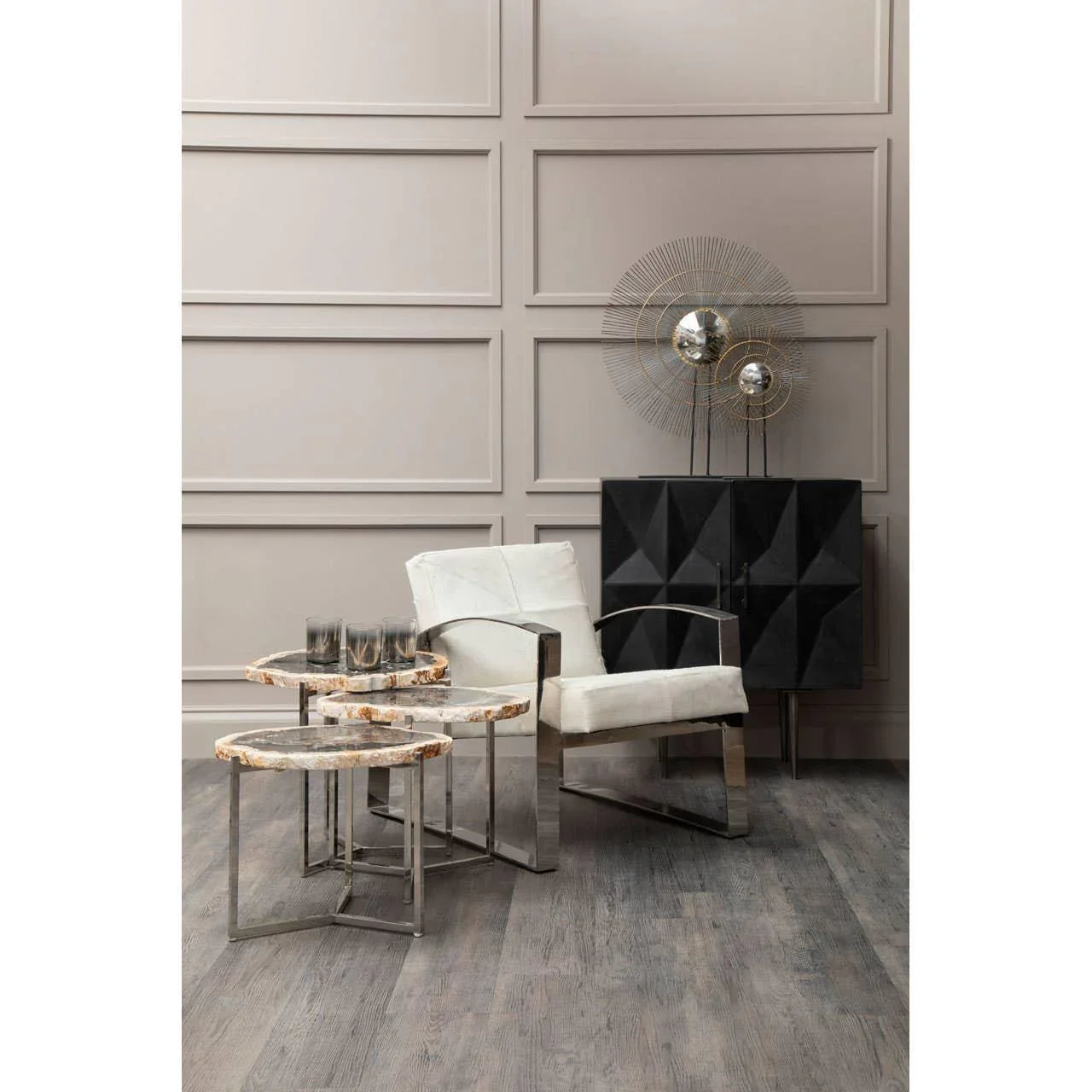 Modern marble nest of tables with chrome legs next to white armchair in living room