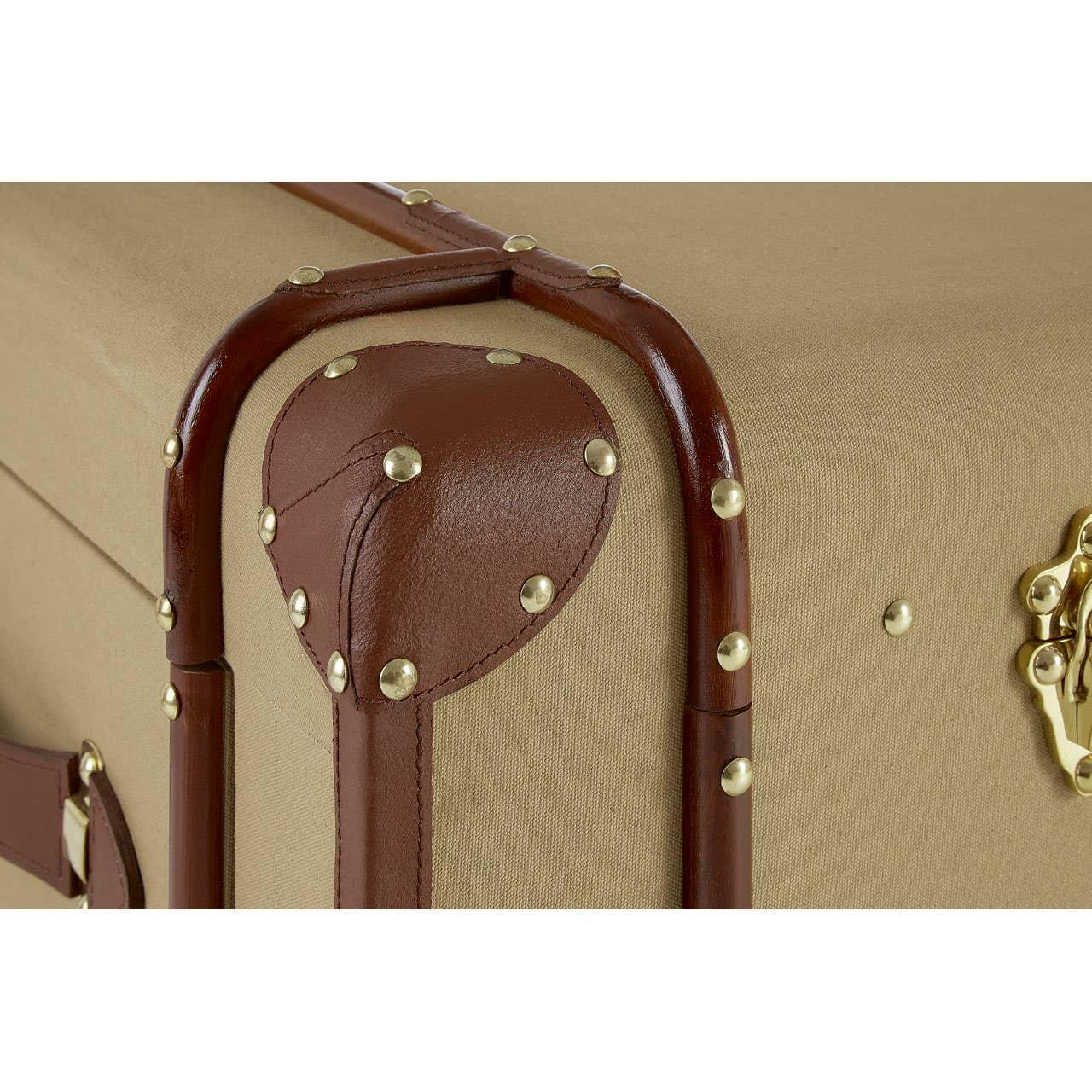 Corner detail of storage trunk with tan canvas, brown faux leather trim, and brass studs