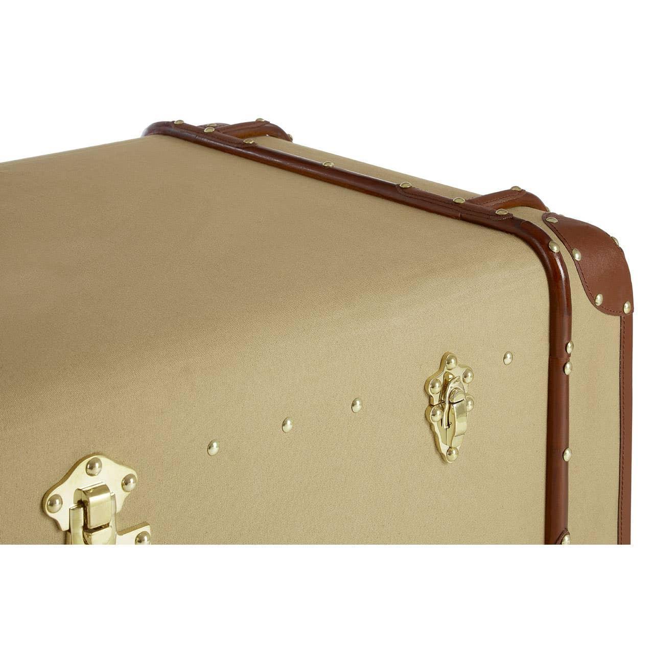 Corner view of beige storage trunk with brown leather trim and gold metal latches