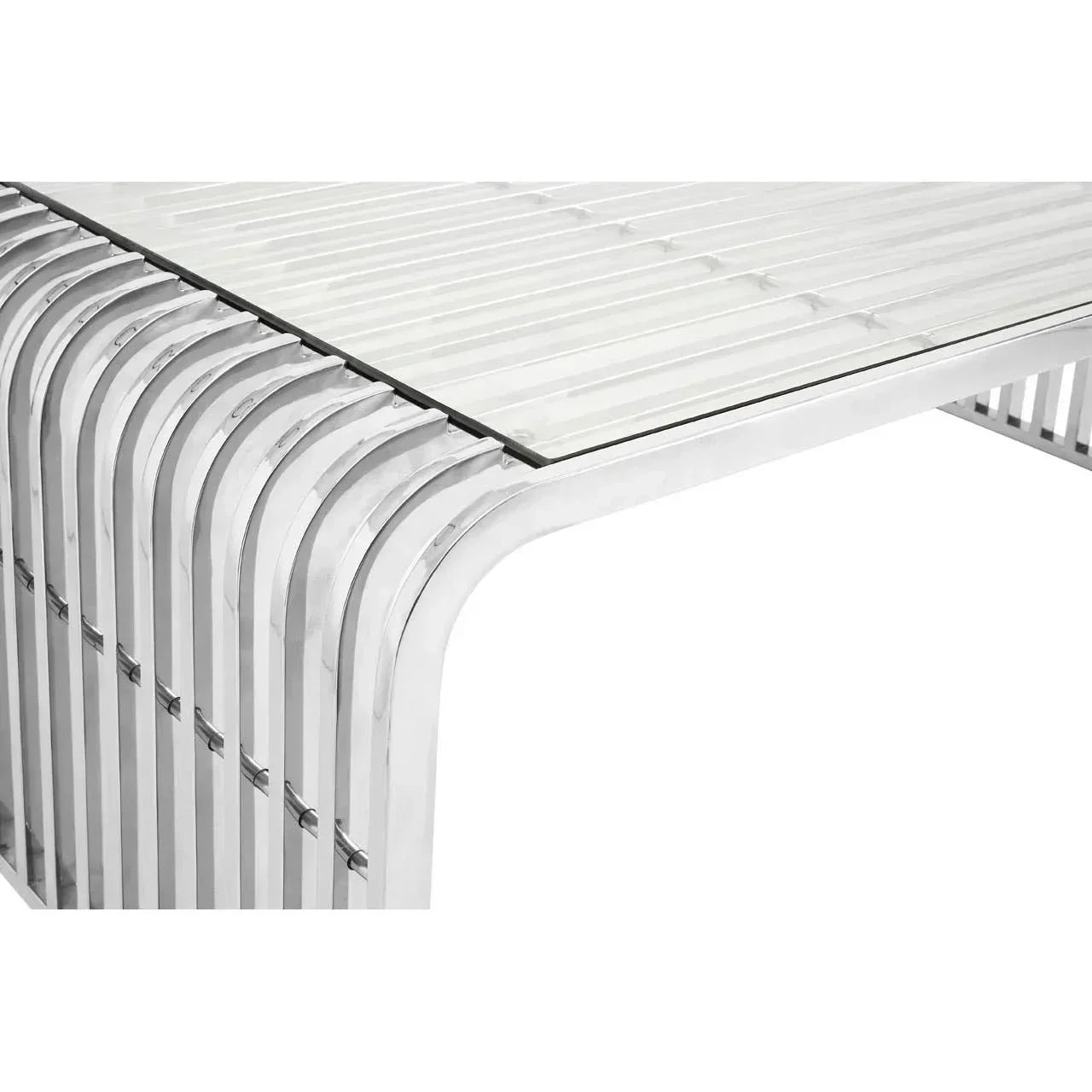 Modern dining table with clear glass top and polished chrome metal frame, corner view