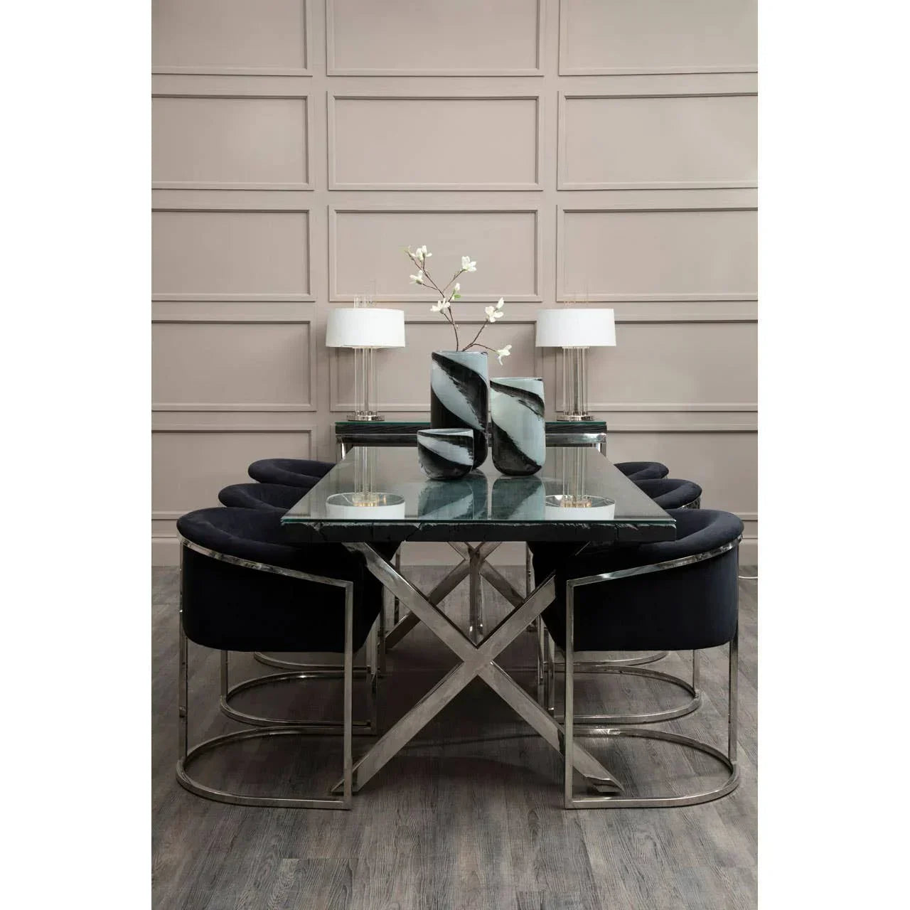 Glass dining table with chrome base and navy velvet chairs, modern decor and lamps