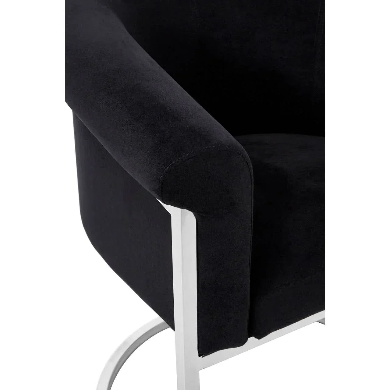 Black velvet upholstered armchair with chrome metal frame, close-up on arm and base
