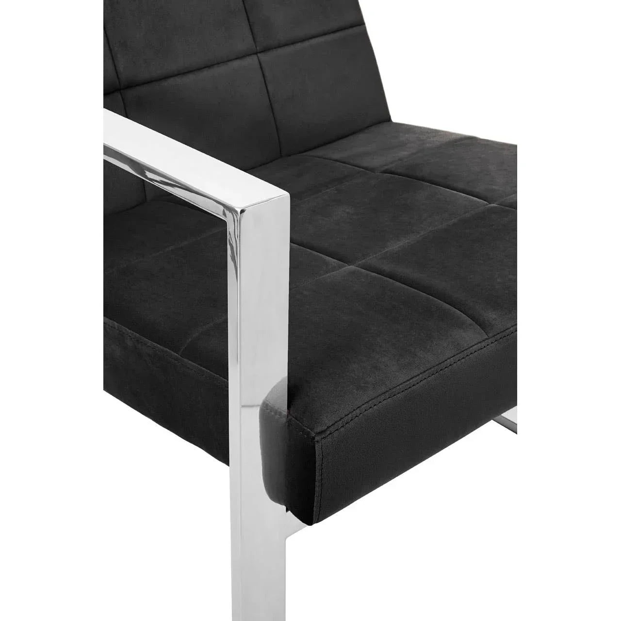 Black velvet dining chair with chrome armrest and stitched seat detail, close-up view