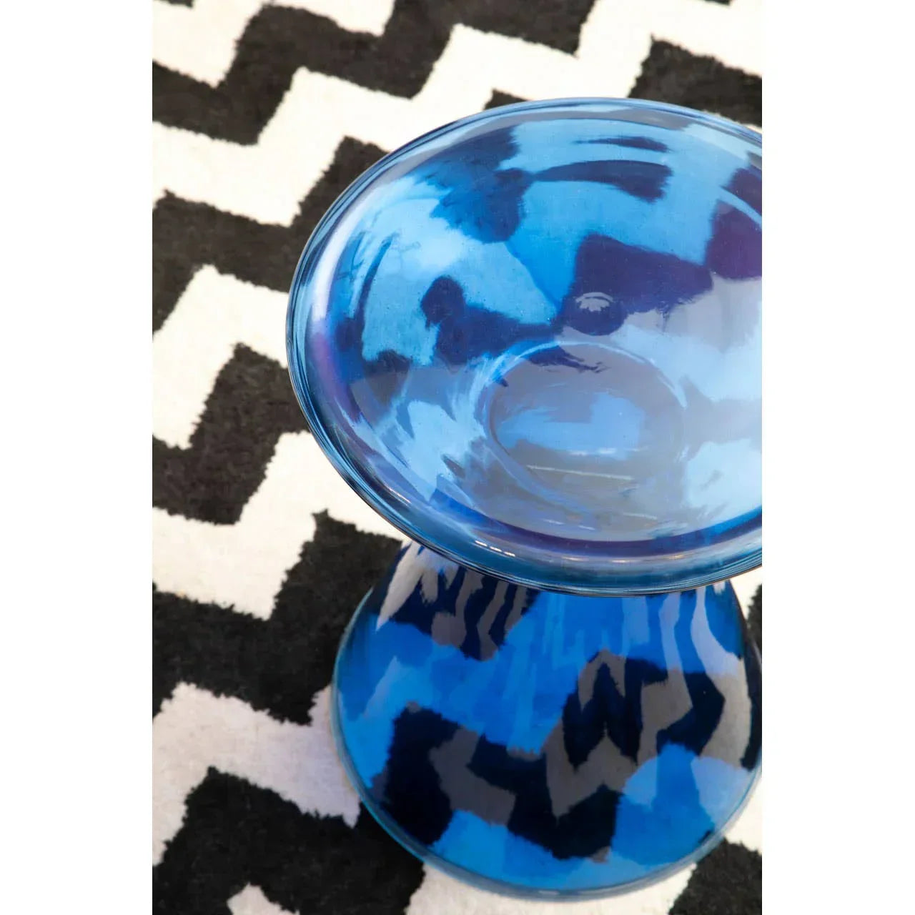 Blue glass side table on black and white geometric patterned rug