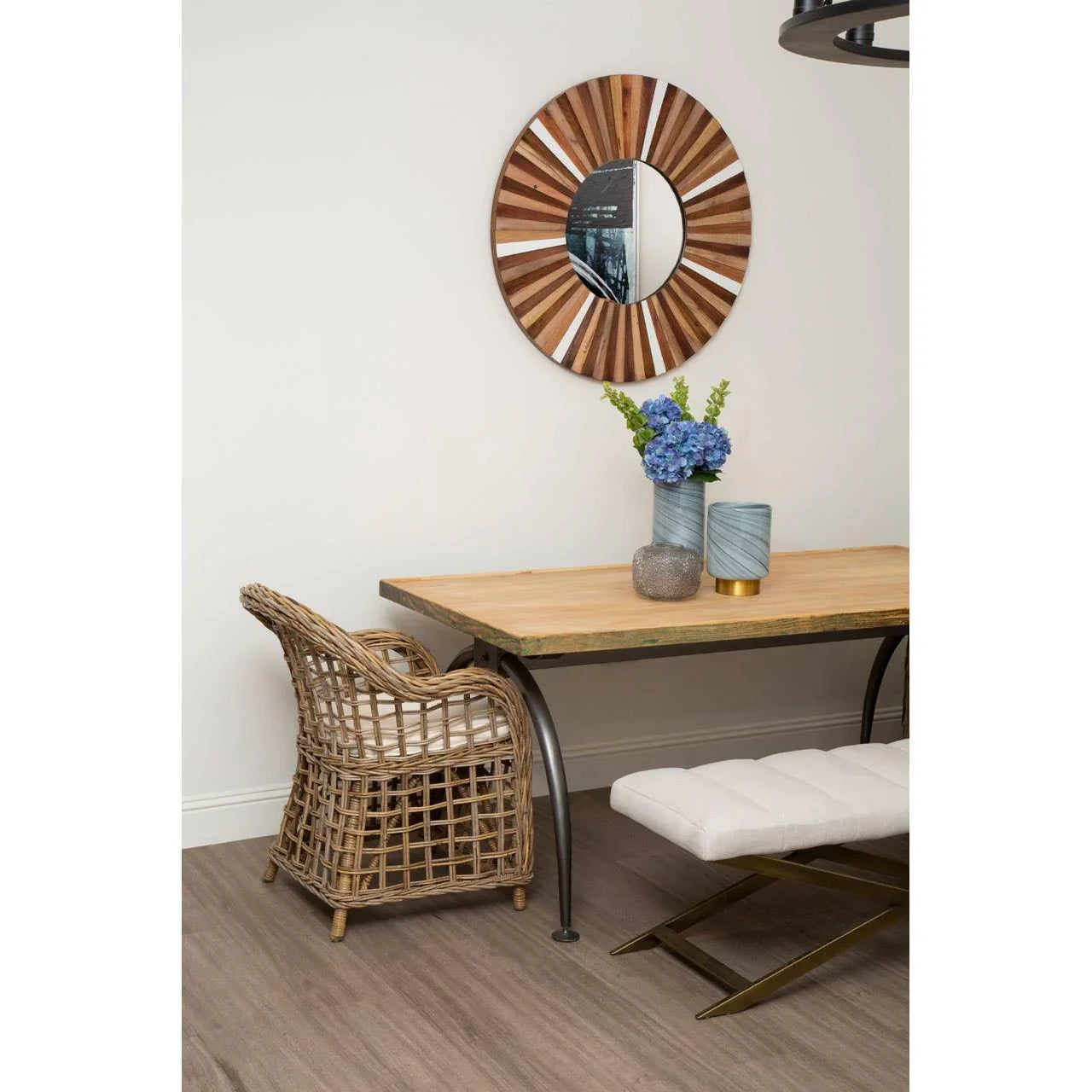 Rattan dining chair with cushion beside wooden dining table and decorative round wall mirror