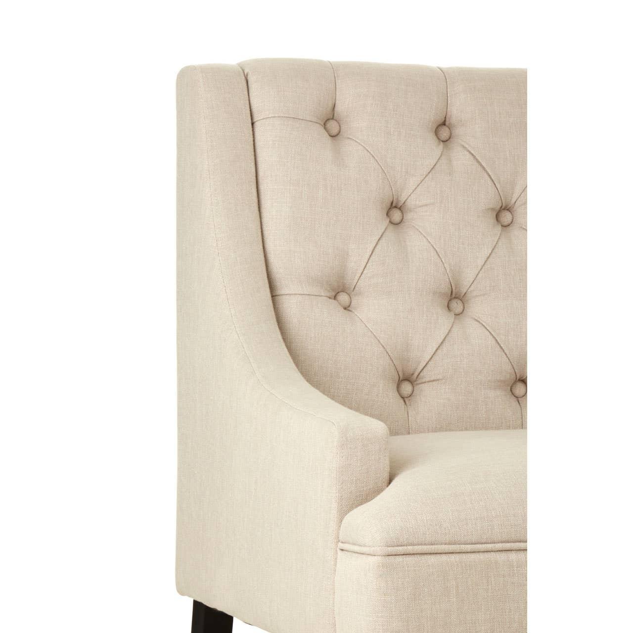 Beige fabric armchair with button-tufted backrest and dark wood leg, closeup view