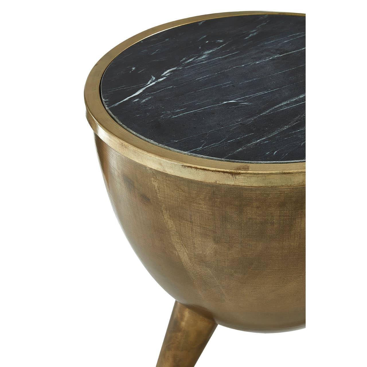Round side table with black marble top and gold metal base, partial close-up view