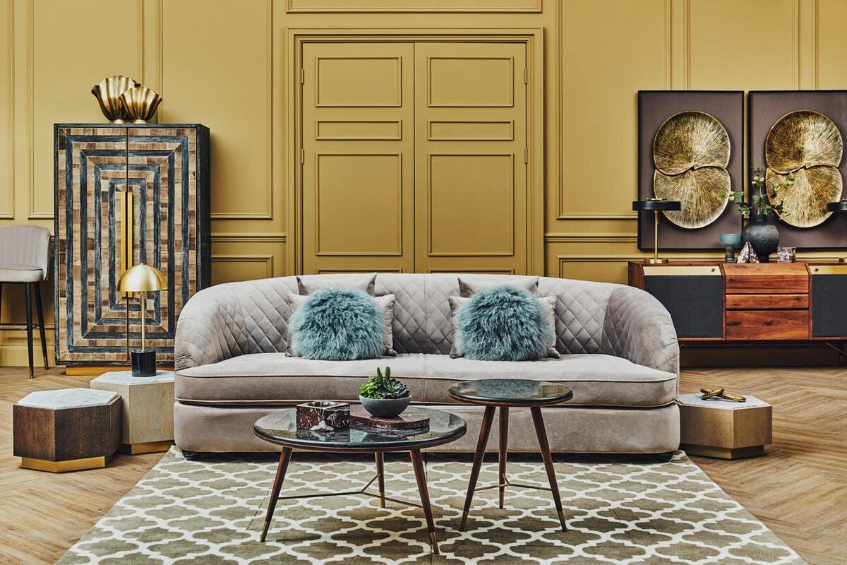 Velvet sofa with quilted detail and blue cushions, coffee tables, and sideboard in modern living room