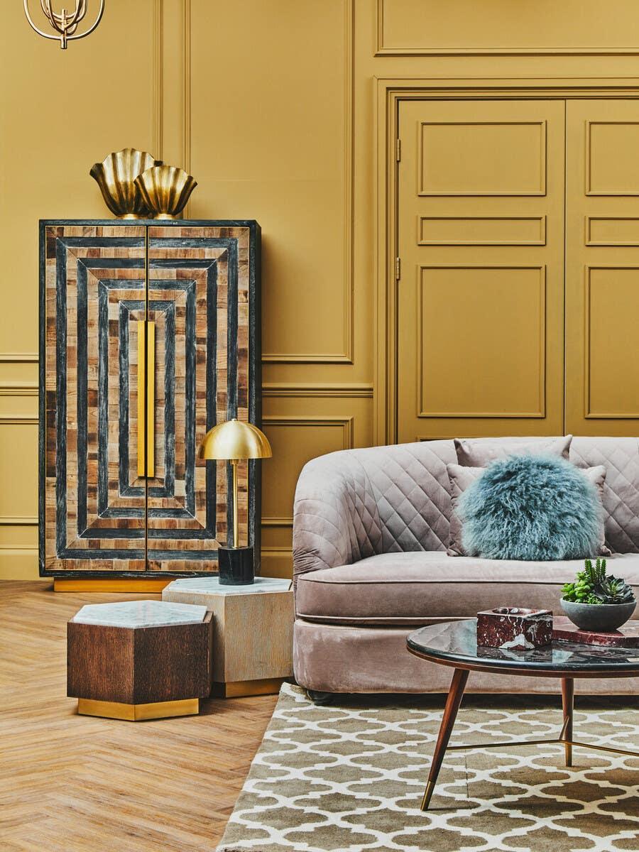Modern velvet sofa with blue cushion, geometric coffee table, and patterned rug in living room