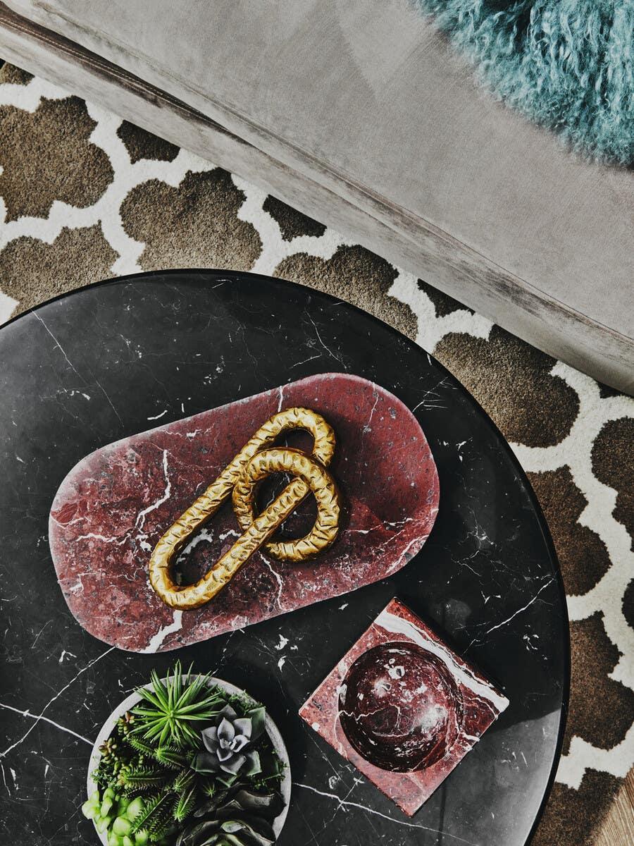 Black marble coffee table with red marble tray, decorative gold link and faux succulents