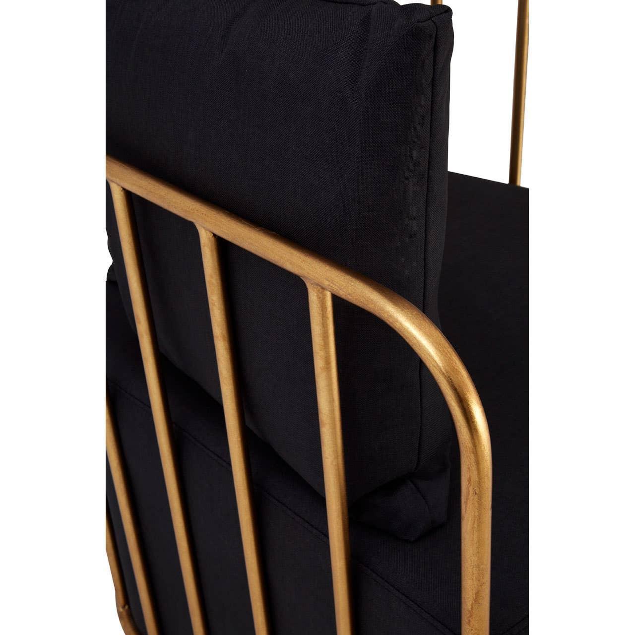 Black sofa with gold metal frame and plush back cushion, close-up rear view
