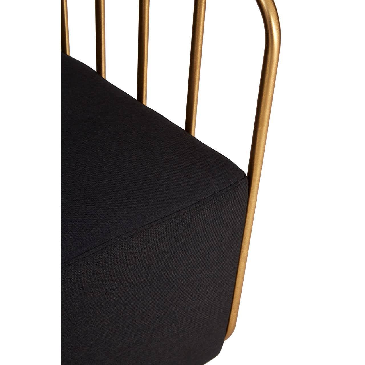 Closeup of a black fabric sofa seat with gold metal frame