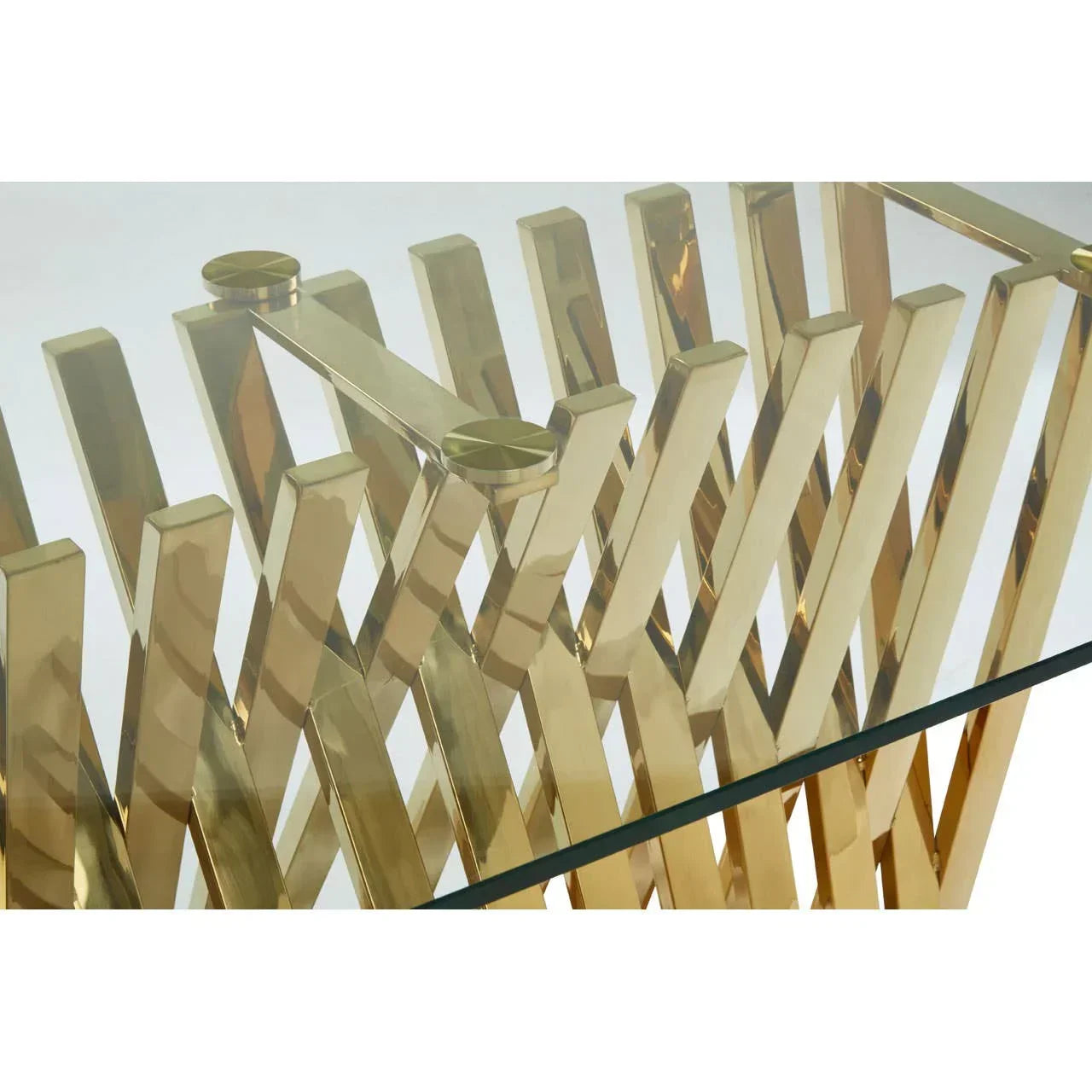 Gold metal coffee table base with intersecting bars and clear glass top detail view