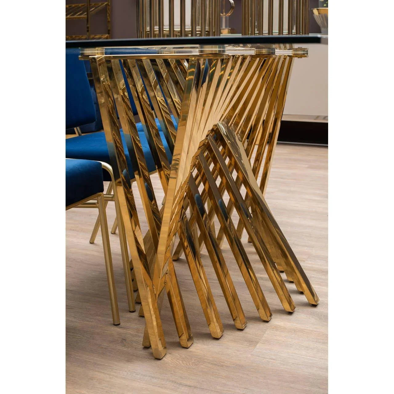 Glass top dining table with gold metal geometric base and blue velvet dining chairs