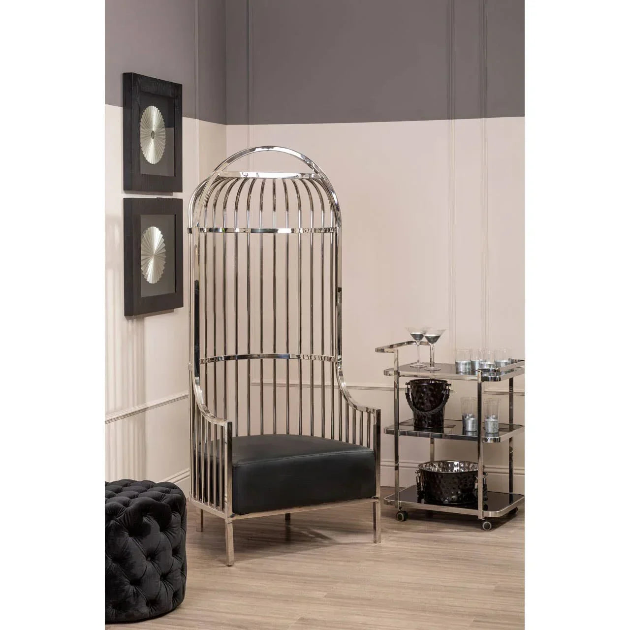 Modern chrome accent chair with black cushioned seat beside glass bar cart in living room