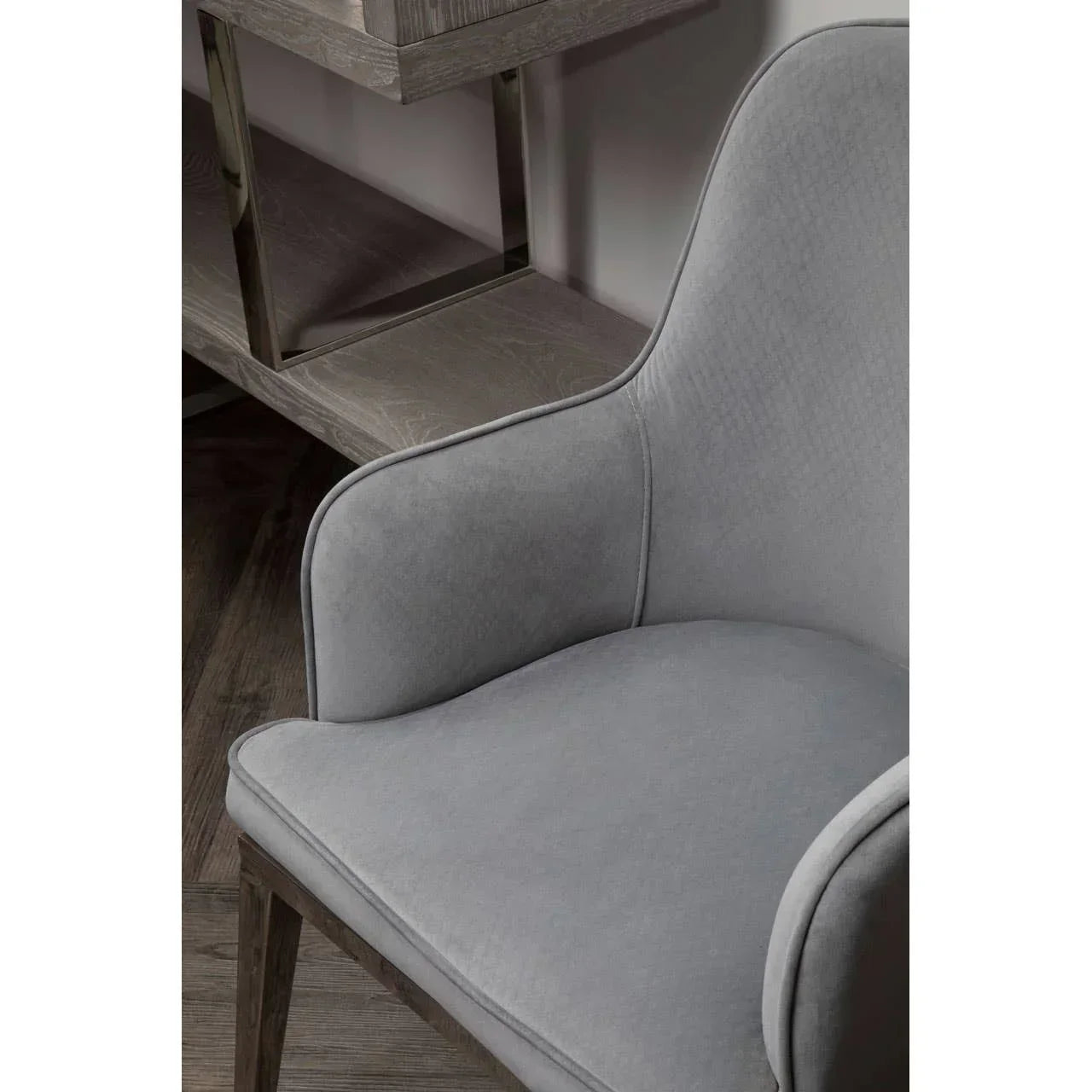 Grey upholstered armchair with curved backrest beside wooden console table