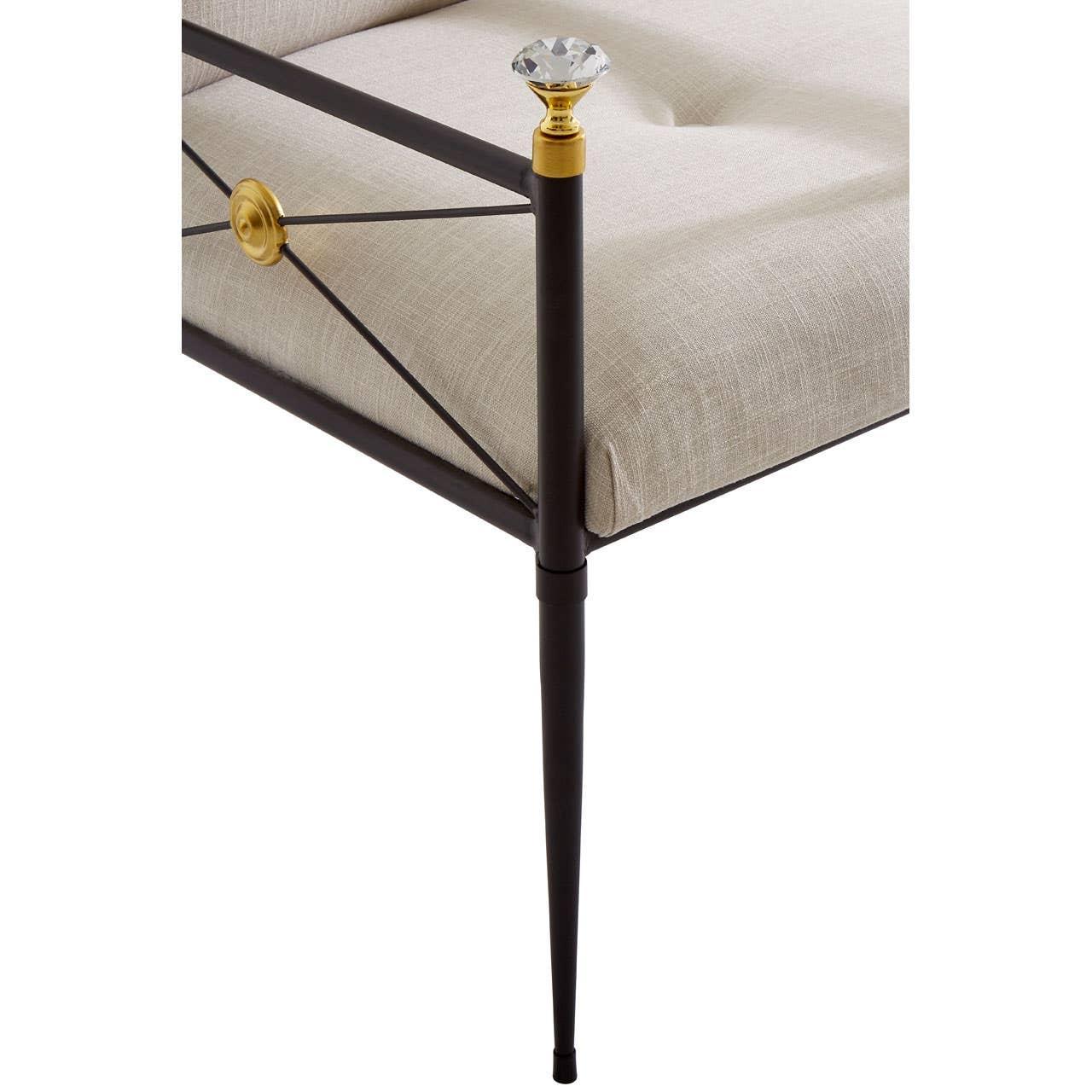 Corner of metal bed frame with beige upholstered cushion and gold accent detail