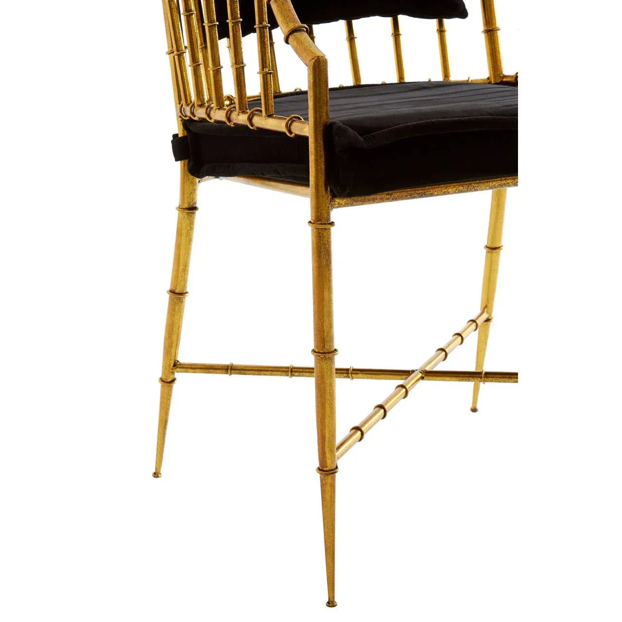 Gold metal dining chair with spindle legs and black cushioned seat, close side angle