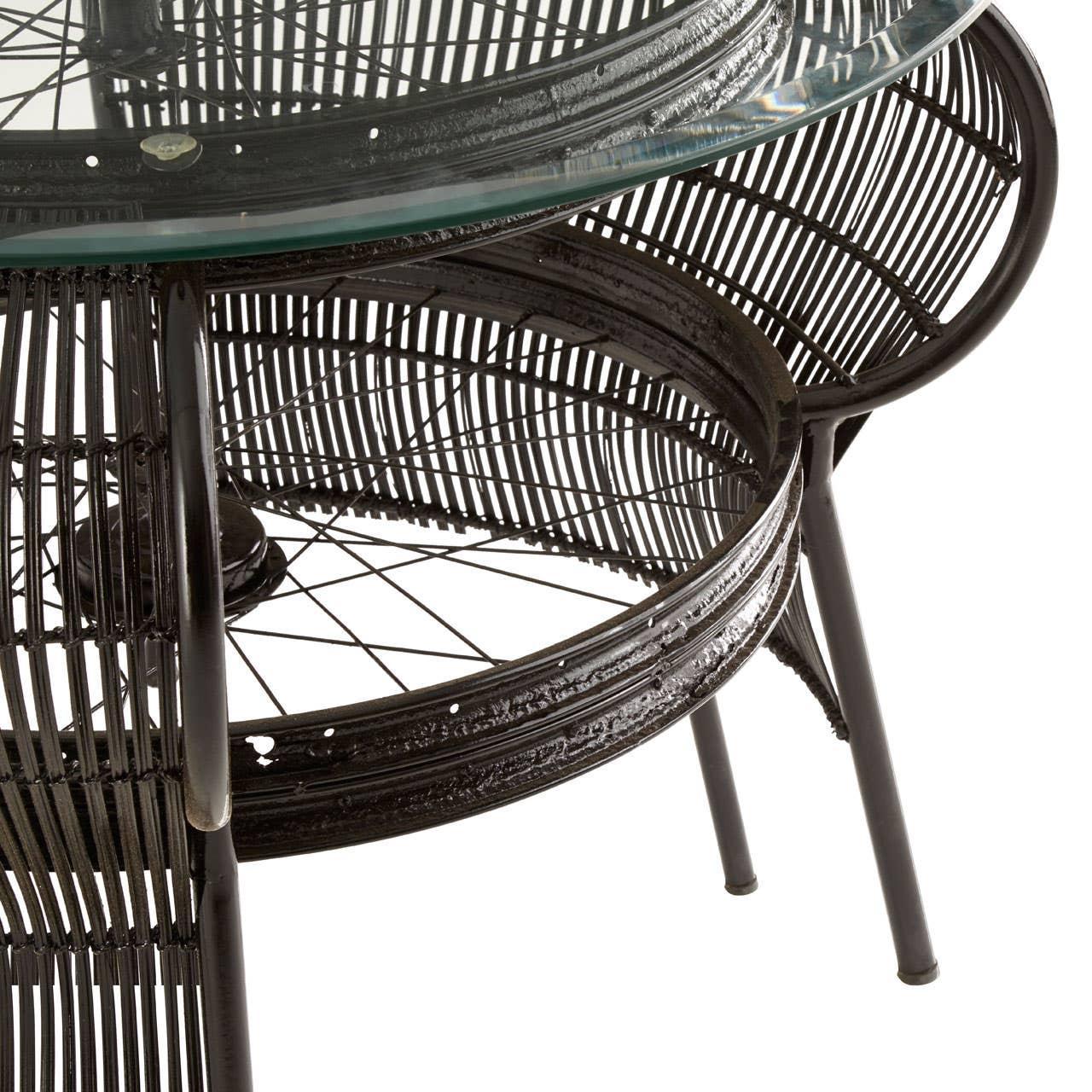 Black rattan coffee table with circular glass top and metal legs, close-up view