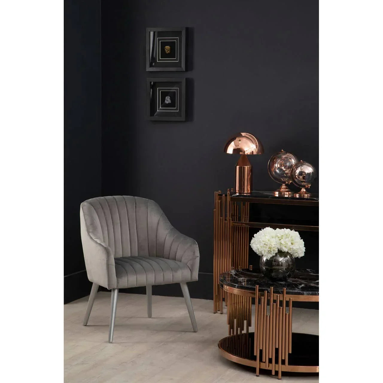 Grey velvet accent chair beside black and gold console table with copper lamp and decor